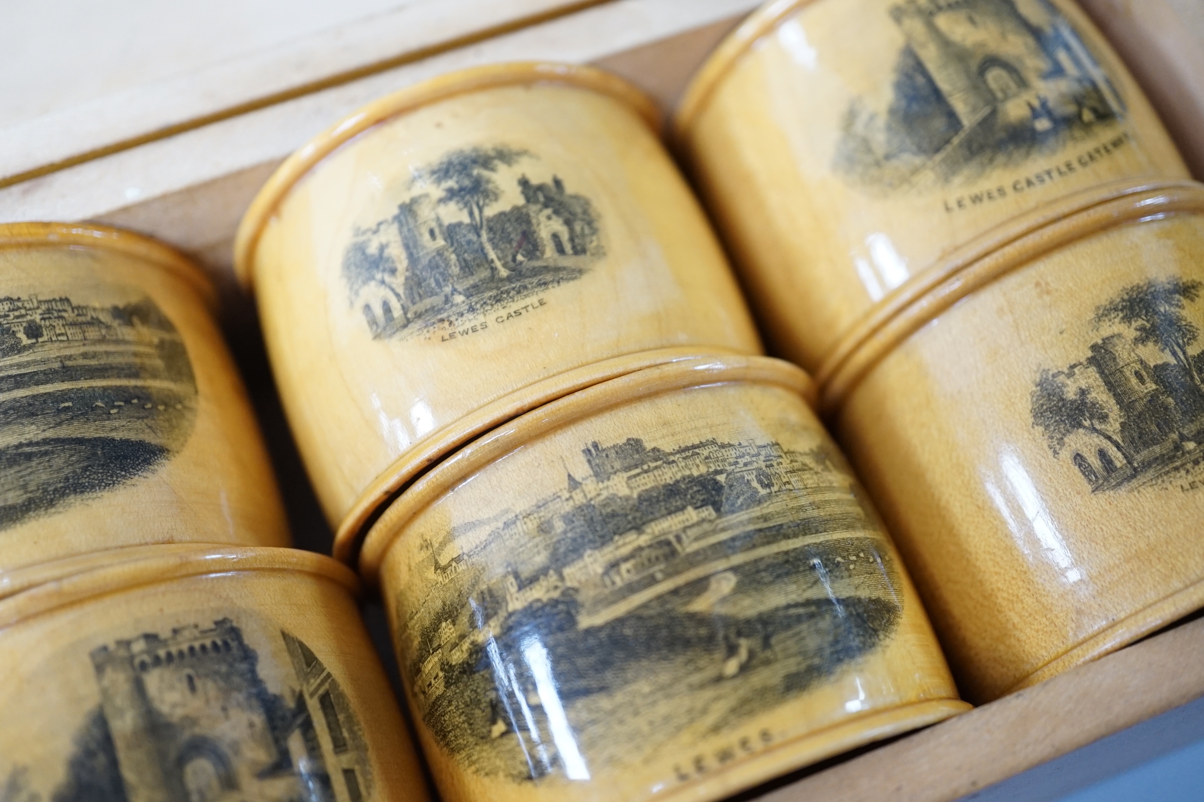 A set of 6 late 19th century mauchline ware napkin rings decorated with scenes of Lewes, housed in matching box. 18cm